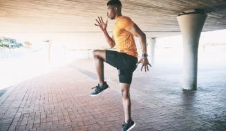 Homem em movimento realizando exercícios de treinamento funcional ao ar livre, em um ambiente urbano, destacando a importância da atividade física.