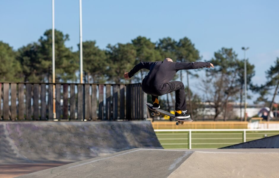 Atleta fazendo manobra de skate no ar em pista de skate.