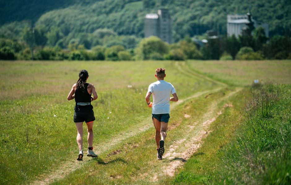 Casal correndo em um caminho rural, cercado por natureza exuberante, ideal para atividades ao ar livre e corrida. Uma ótima inspiração para corredores!