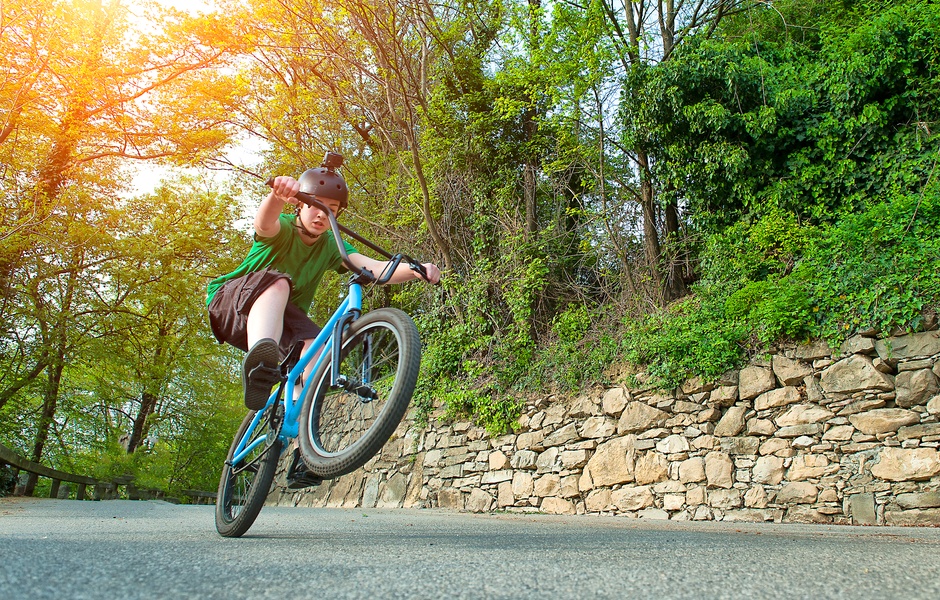 Criança praticando manobras em uma bicicleta em um caminho rodeado pela natureza durante um dia ensolarado