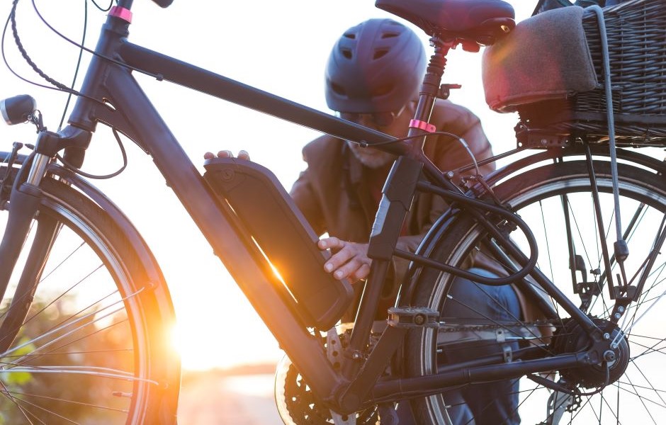 Pessoa ajustando uma bicicleta elétrica ao pôr do sol, com foco na bicicleta moderna e sustentável, ideal para transporte urbano ecológico.