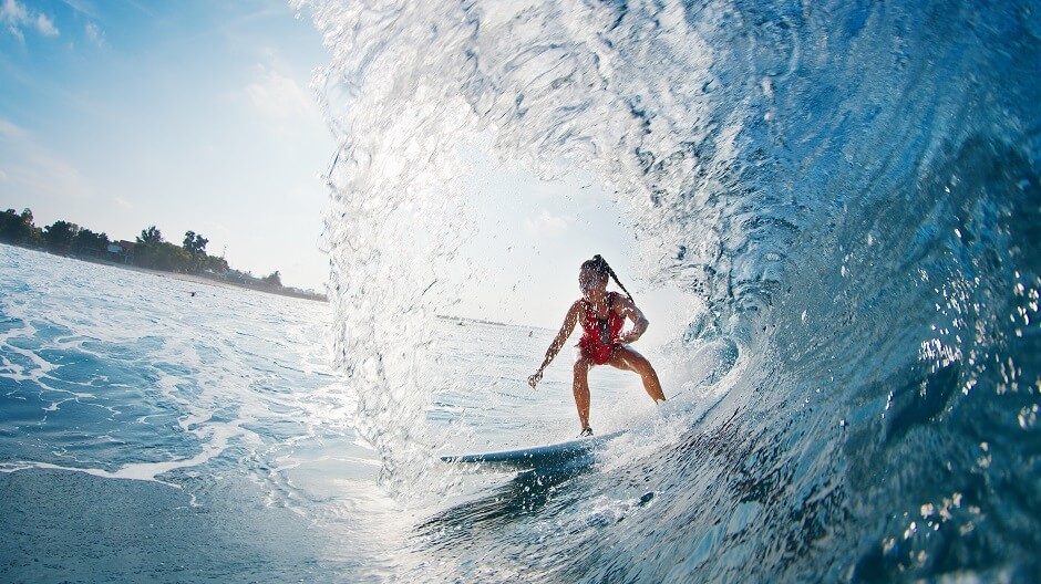 Atleta feminina surfando uma onda no mar
