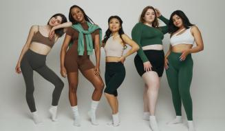 Cinco modelos femininas posando em um fundo neutro. Destacando uma variedade de biotipos corporais.