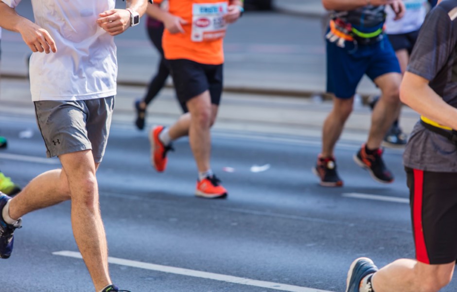 Pessoas correndo em uma rua durante uma prova, vestindo roupas esportivas e tênis de corrida.