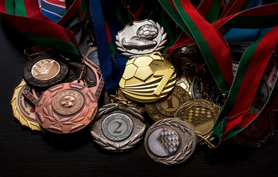 Imagem de várias medalhas de diversos tamanhos, formatos e cores.