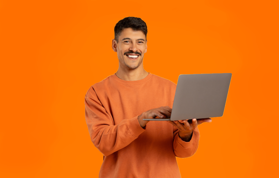 Foto de homem em pé segurando um notebook e sorrindo.