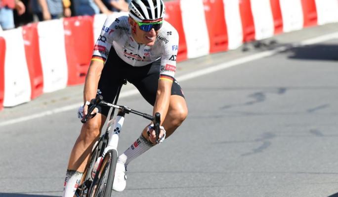 Ciclista profissional em competição, usando capacete, óculos esportivos e uniforme de alta performance, pedalando com força durante uma corrida de estrada.