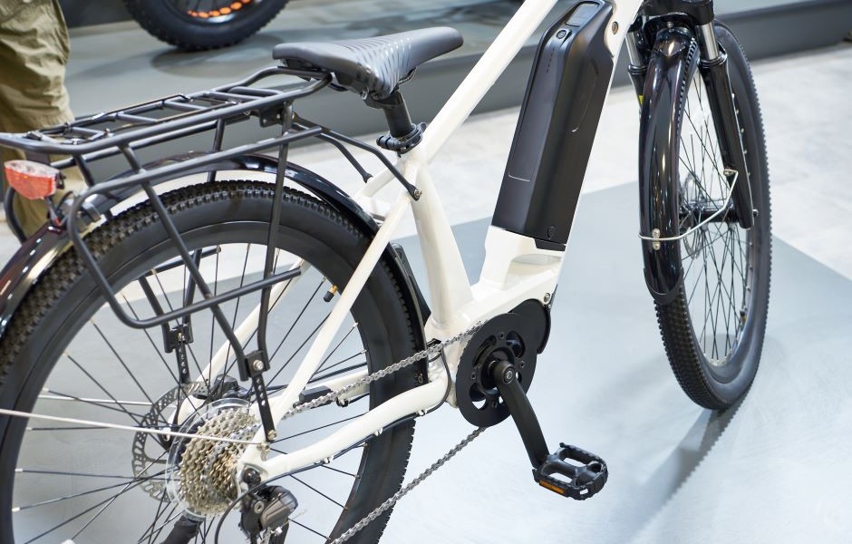 Bicicleta elétrica moderna com quadro branco, motor embutido, rodas robustas e carrinho de carga, ideal para deslocamentos sustentáveis e econômicos.