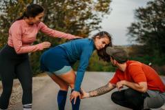 Uma mulher e um homem ajudam uma atleta machucada durante um evento esportivo.