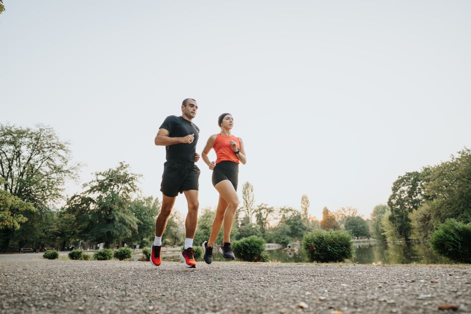 Dois atletas, um homem e uma mulher, correndo em um parque as margens de um lago
