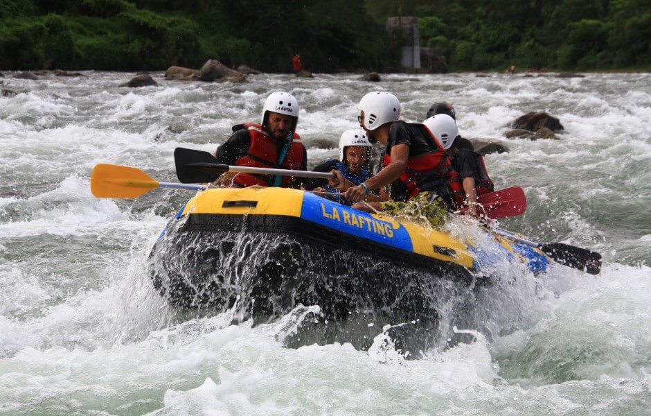 Imagem de uma equipe em um bote enfrentando um rio agitado.